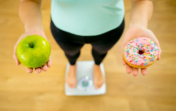 Fotos de dos manos de una mujer sosteniendo una manzana y en la otra un dulce