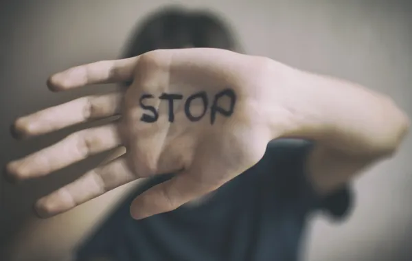 Foto de una mujer que se tapa la cara con la palma de una mano que dice Stop parar