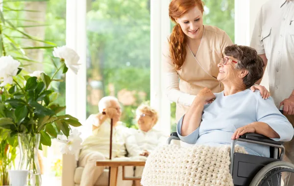 Foto de una mujer en silla de ruedas atendida por una enfermera