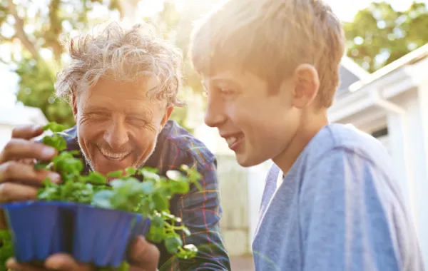 Foto de un niño y de un adulto viendo juntos una maceta con una planta