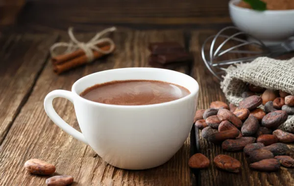 Foto de una taza de chocolate rodeada de frutos de cacao