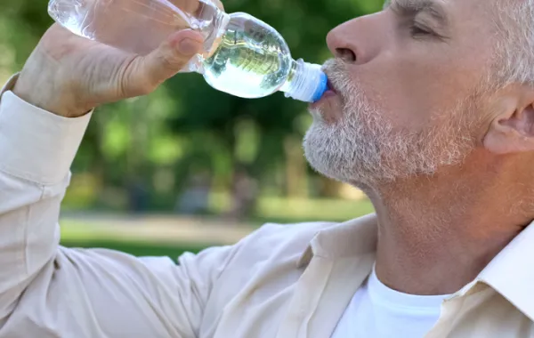 Foto de un señor adulto bebiendo agua de una botella