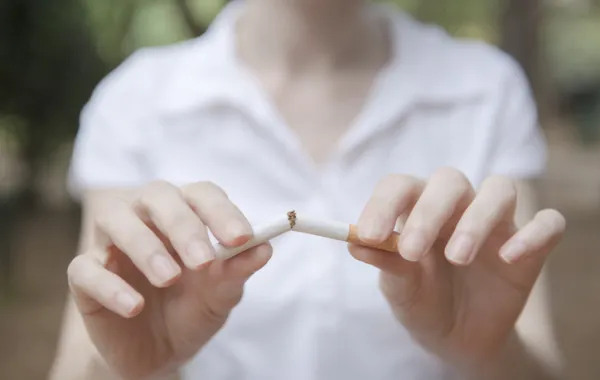 Foto de una personas que rompe un cigarrillo por la mitad