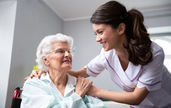 Foto de una señora mayor acompañada por una enfermera joven