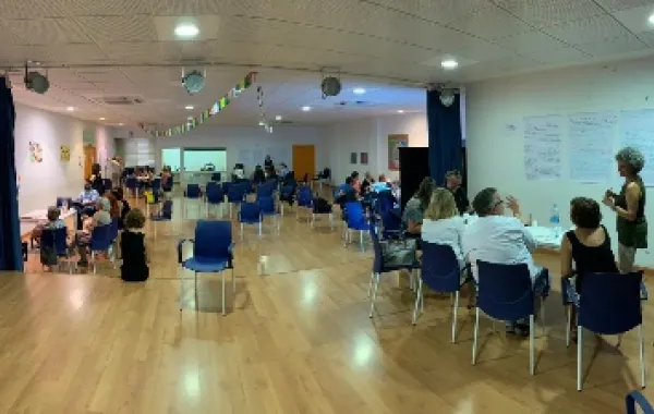 Foto de una sala con varios personas repartidas en grupo trabajando