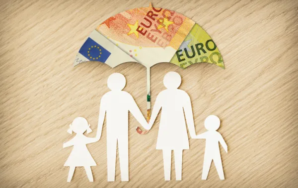 Foto de las figuras de una familia bajo un paragüas pintando con billetes de dinero