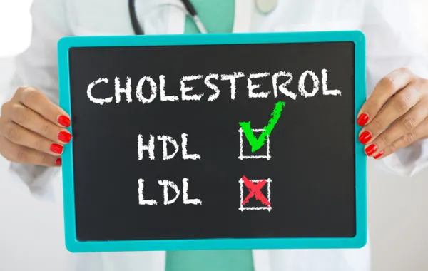 Foto de una manos de una médico que sostiene un cartel con la palabra colesterol HDL y LDL