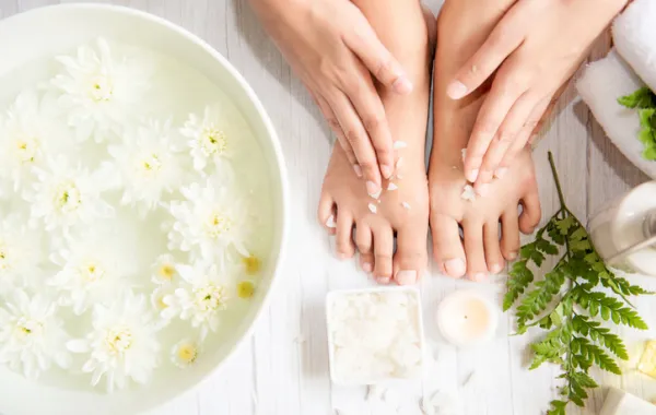 Foto de uno pies rodeados de una vasija con agua  y cremas