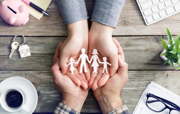 Foto de unas manos que sostienen un recorte con una familia