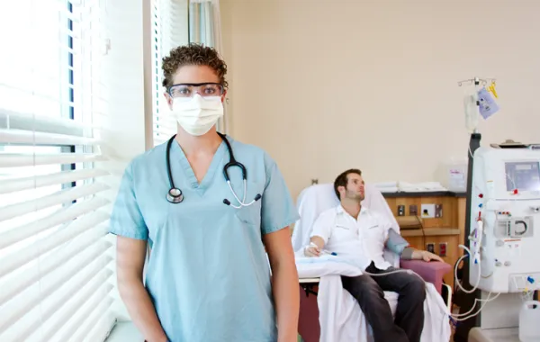 Foto de un enfermo recibiendo tratamiento y delante de él la doctora que lo cuida