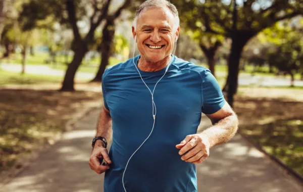 Foto de un señor adulto haciendo deporte corriendo por un parque