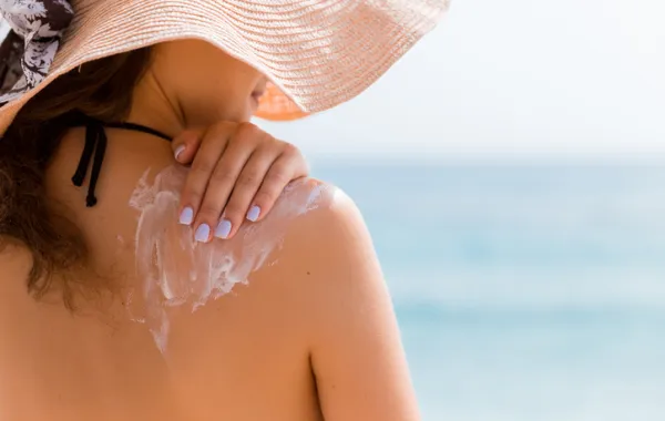 Foto de una chica de espaldas que se pone crema protectora en el hombro