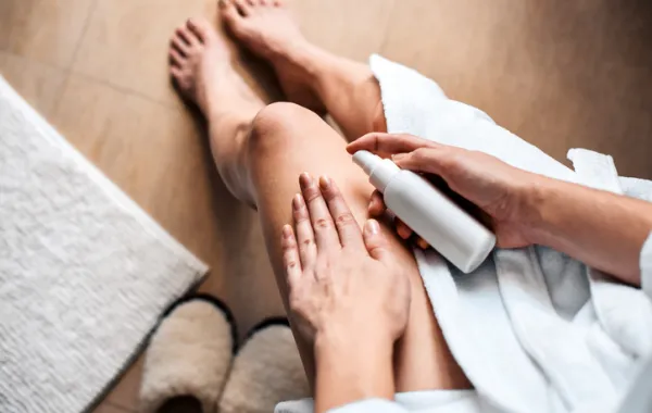 Foto de una mujer adulta que se hidrata las piernas con una crema