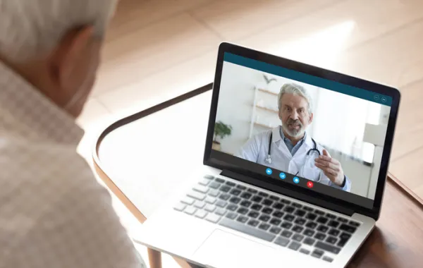 Foto de un señor mayor que está hablando por videoconferencia con su medico