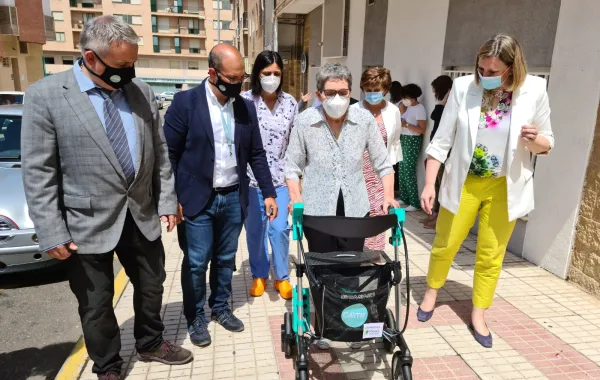 Foto de varias personalidades acompañando a una persona con un andador especial
