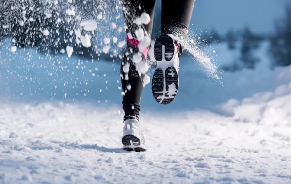 Foto de unas piernas por detras corriendo en la nieve
