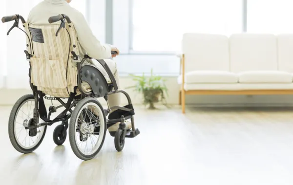 Foto de una señora en silla de ruedas en un salon de casa