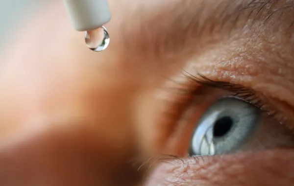 Foto con el primer plano de un ojo y una gotas de liquido que recibe