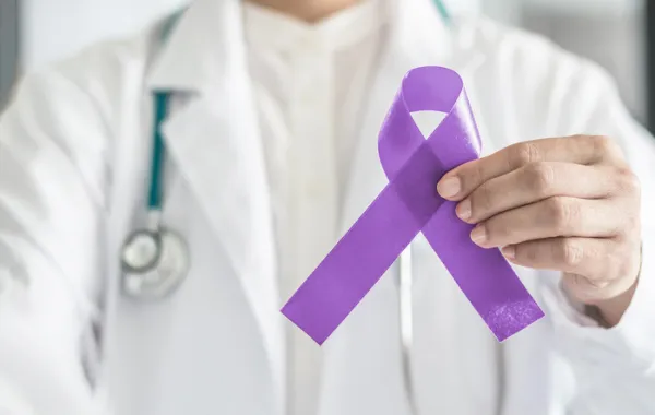 Foto de la imagen de un médico que sostiene en una mano un lazo morado