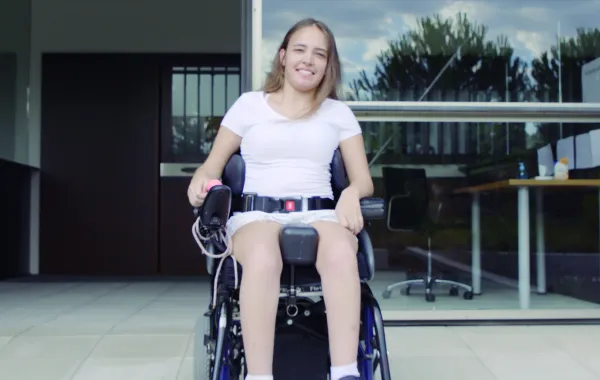Foto de una chica joven en silla de ruedas delante de un edificio