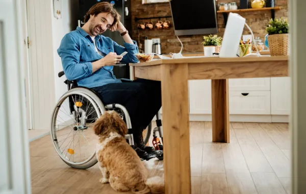 Foto de una chico joven en silla de ruedas en su cocina
