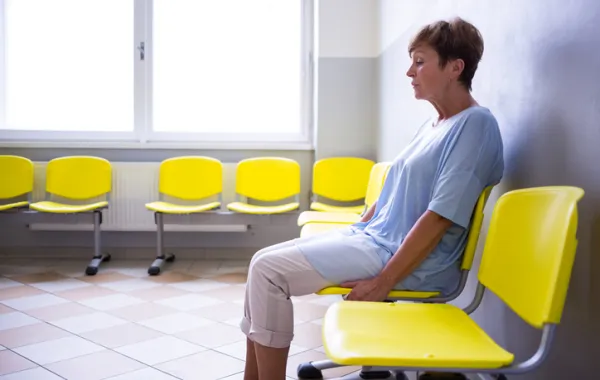 Foto de una mujer mayor sentada en una silla de una sala de un hospital