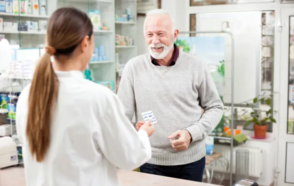 Foto de una farmacéutica entregando medicamentos a un señor