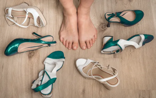 Foto de unos pies descalzos rodeados de varios tipos de sandalias