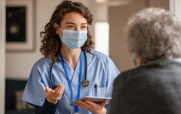 Foto de una médico hablando con una persona mayor
