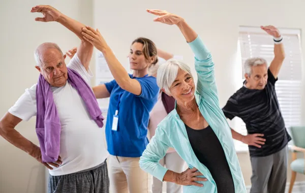 Foto de varias personas mayores haciendo ejercicio con una fisioterapeuta
