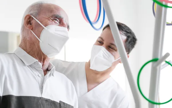 Foto de un señor mayor acompañado de un profesional sanitario