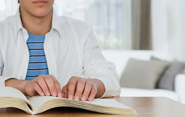 Foto de una persona leyendo un libro en braille