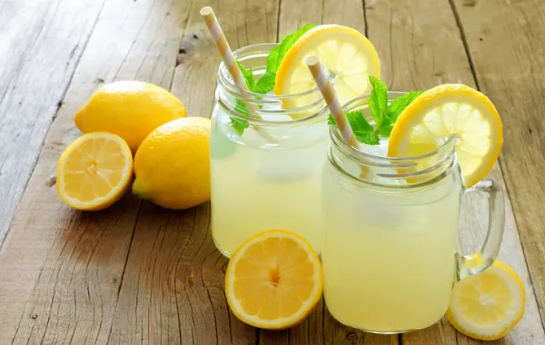 Foto con dos vasos de granizado de limon rodeados de limones