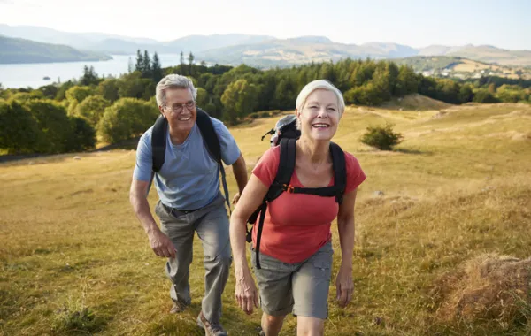 Foto de dos personas adultas de excursión subiendo una montaña