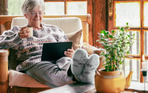 Foto de una señora mayor sentada en un sillón leyendo un libro