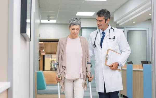 Foto de un medico hablando con una paciente que anda con muletas