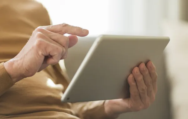 Foto de una manos de persona mayor que sostiene una tablet
