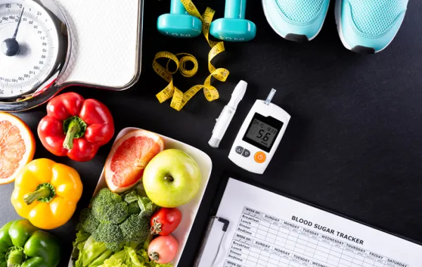 Foto de un aparato para medir el azucar en sangre al lado de varias frutas y verduras