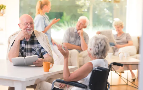 Foto de varias personas mayores charlando en un salón de una residencia