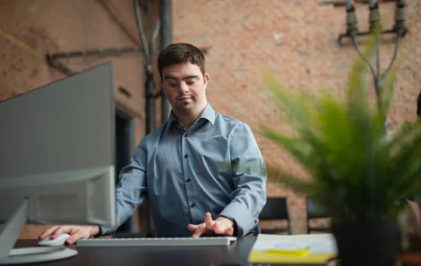 Foto de un joven con sindrome de down trabajando delante de un ordenador