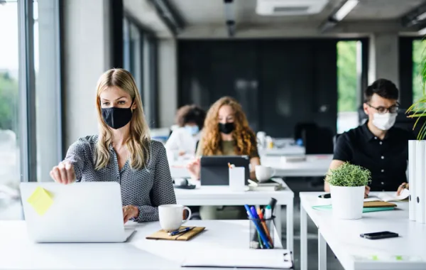 Foto de varias personas sentadas en sus mesas en una oficina y mirando el ordenador