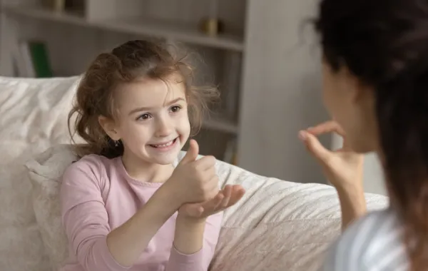 Foto de un niña hablando en lenguaje de signos con su madre