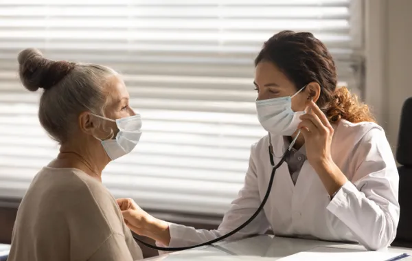 Foto de una señora mayor atendida por una doctora que la osculta en la zona del corazón