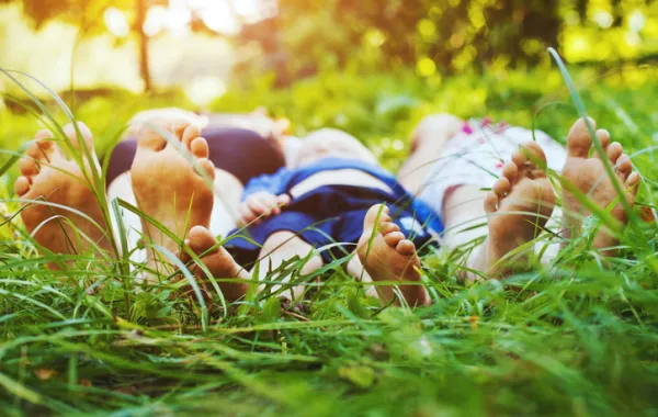 Foto de una familia tumbada en el cesped y con los pies descalzos en primer plano