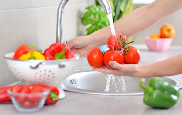 Foto de una manos que están lavando varias verduras