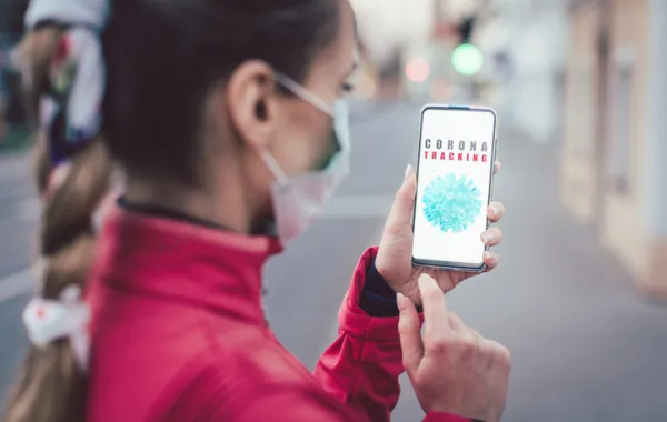 Foto de una chica joven con mascarilla consultando un smartphone