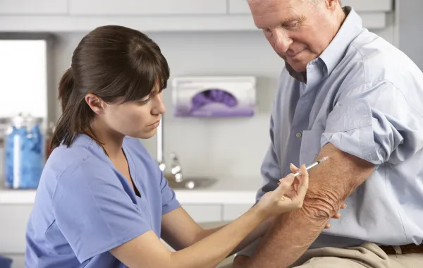Foto de una enfermera poniendo una vacuna a un señor mayor
