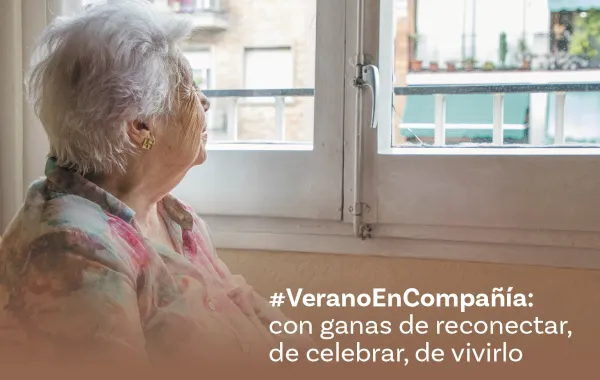 Foto de una mujer mayor mirando por la ventana de su casa
