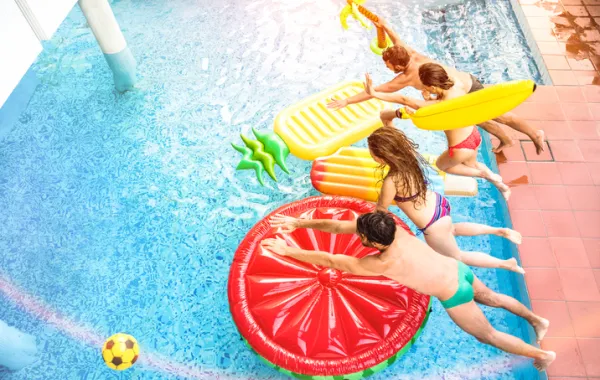 Foto desde arriba de varios jóvenes tirándose a una piscina