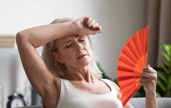 Foto de una mujer mayor con un ábanico y cara agotamiento por calor